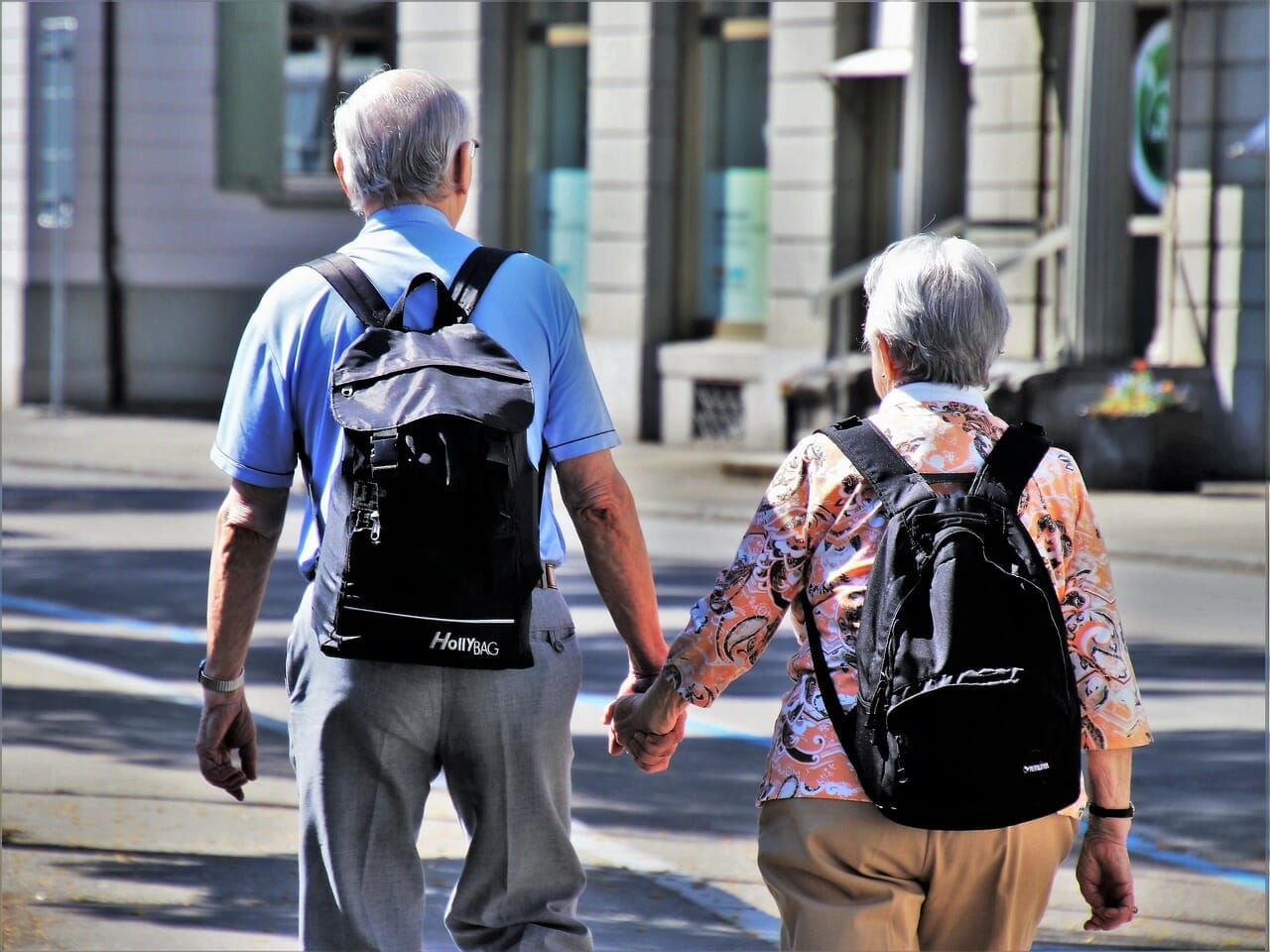Elderly Couple Holding Hands, Exploring the City with Backpacks - Assisting Elderly Foreigners with German Pension